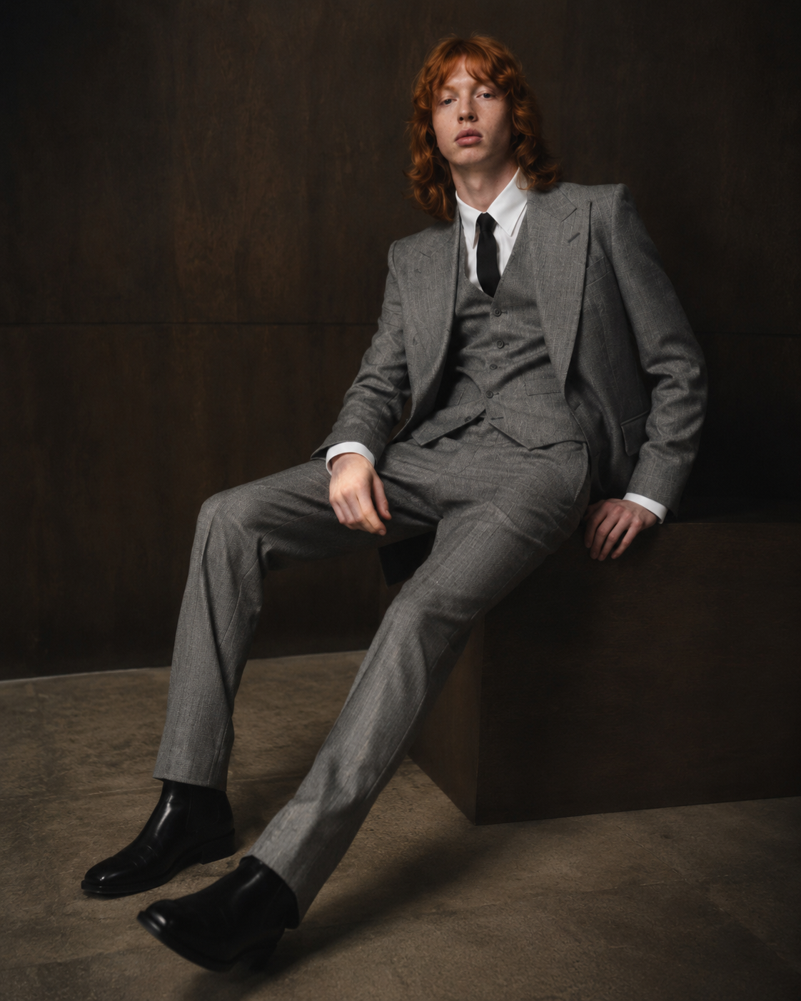 Red-haired model seated in a grey tailored suit