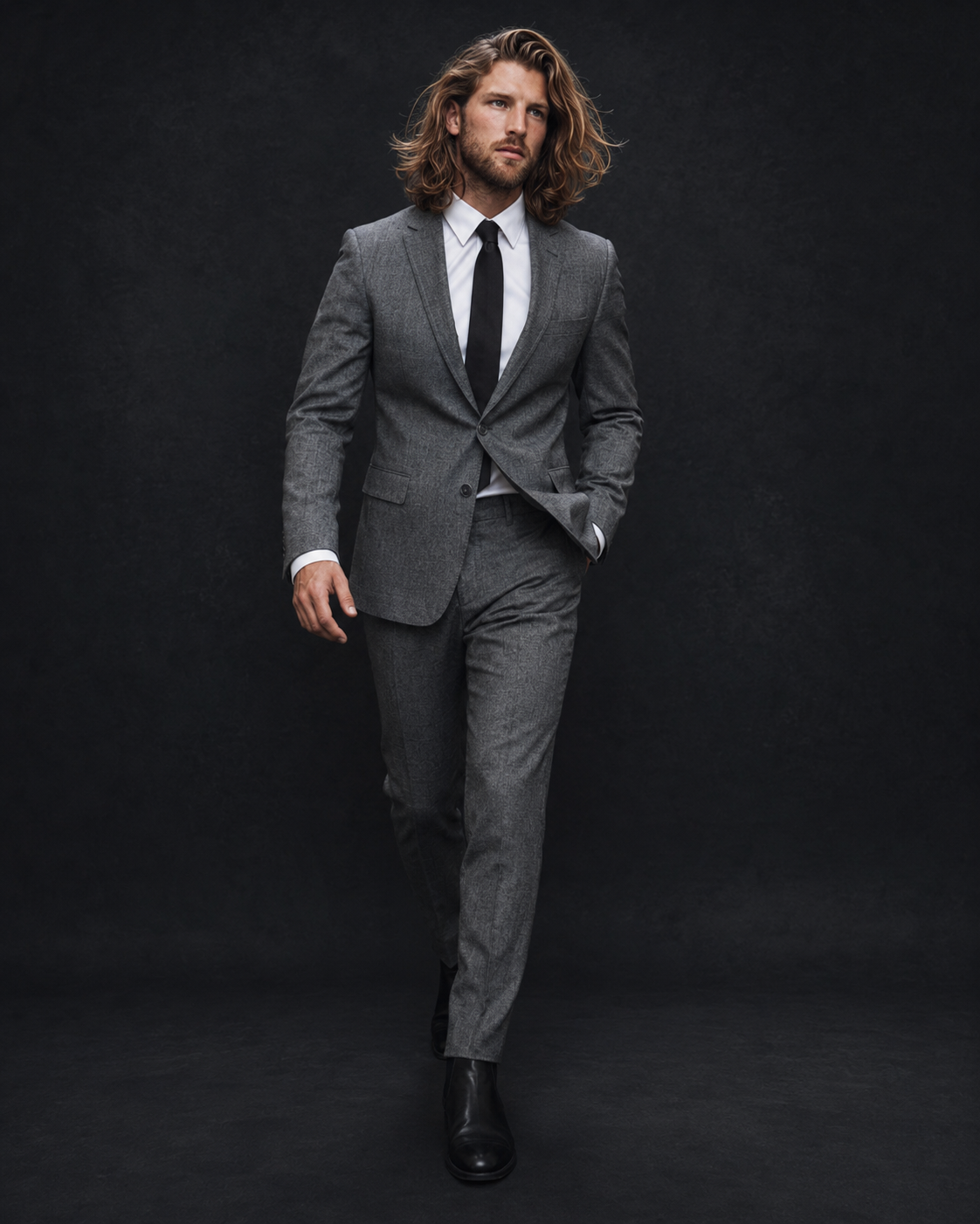 Long-haired model in a grey suit against a dark background