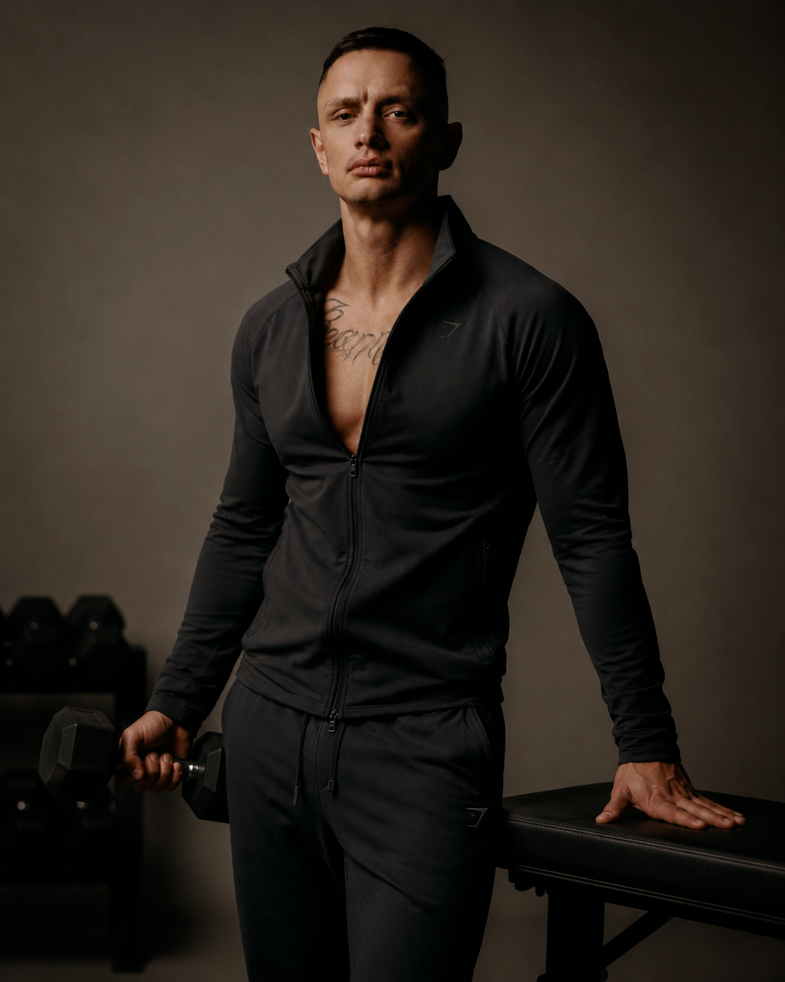 Portrait of a male model in black activewear holding a dumbbell