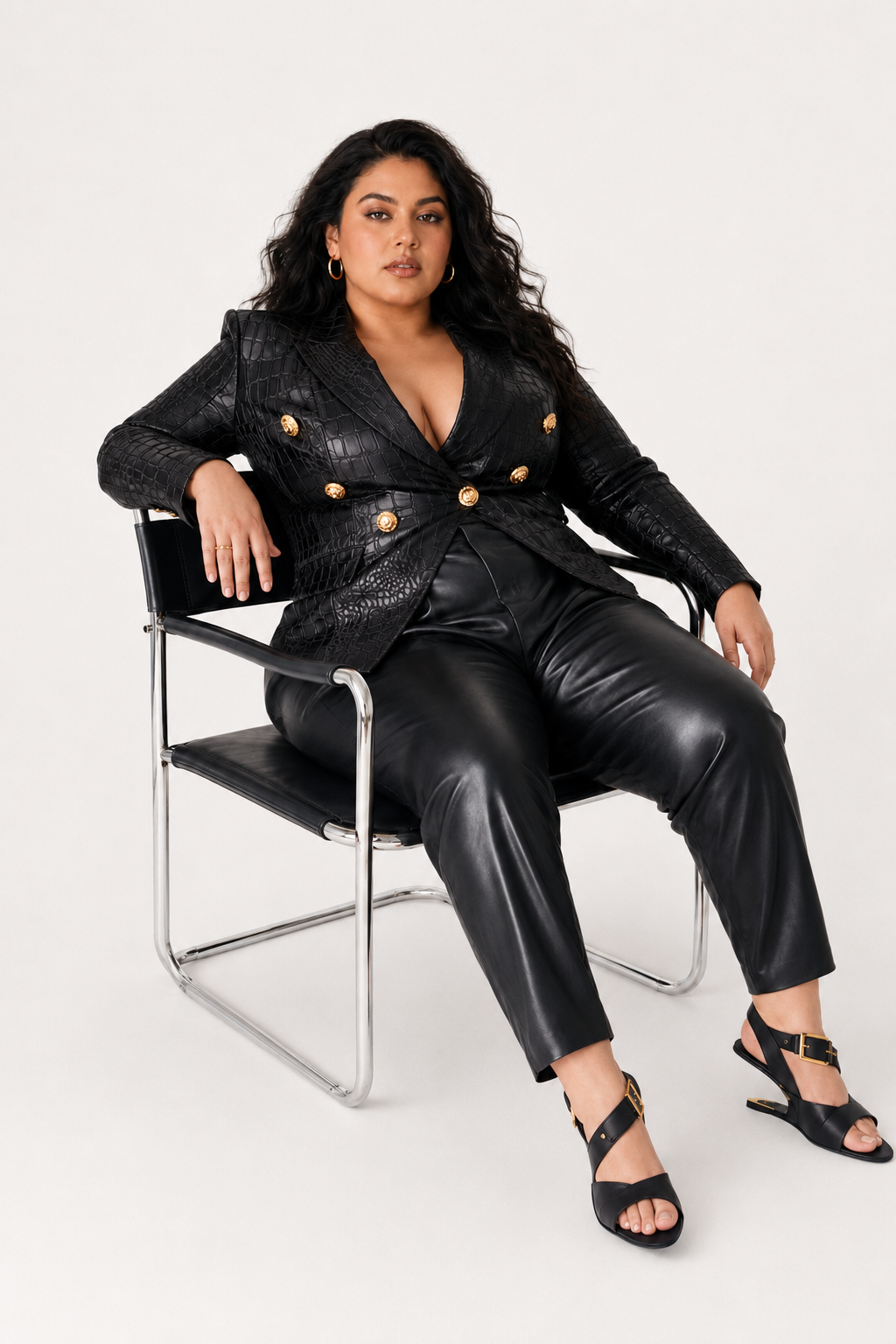 Plus-size model in black crocodile-textured tailoring seated in a chair